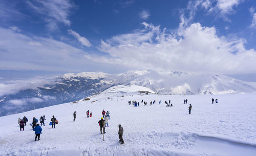 Group of people on snowcapped mountain against sky