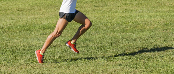 Low section of woman running on field