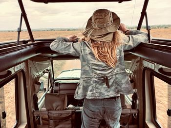 Rear view of woman standing in jeep against sky