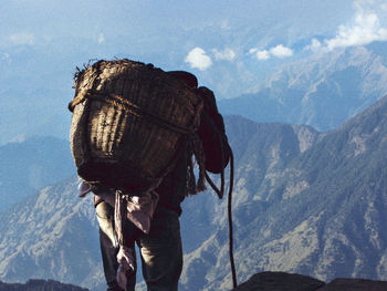 Rear view of man standing on mountain against sky