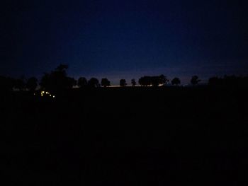 Silhouette trees against clear sky at night