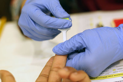 Cropped hands of doctor removing blood sample from patient finger