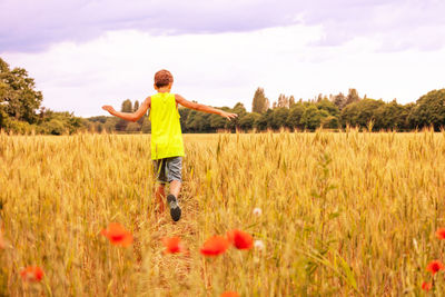 Rear view of woman walking on field against sky