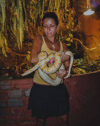 Woman holding python in darkroom