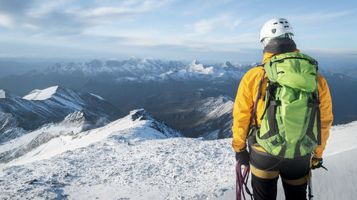 Rear view of man standing on snowcapped mountain