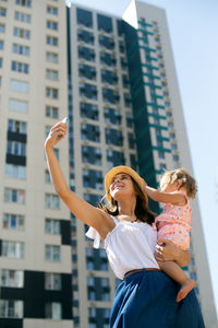 Woman with arms raised standing against buildings in city