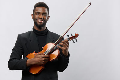 Midsection of man playing violin against white background