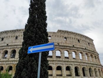 A blue sign with an arrow pointing to the left in front of an arena