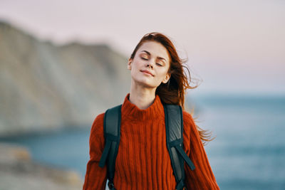 Mid adult woman standing against sea