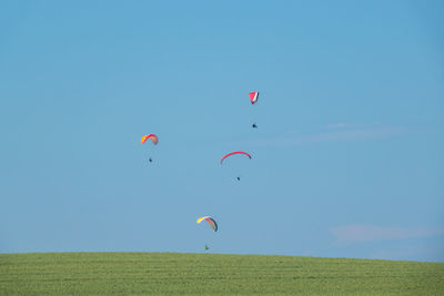 Balloons flying over field against sky