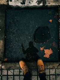 Low section of man standing by water on footpath