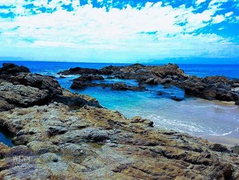 Rock formations by sea against blue sky