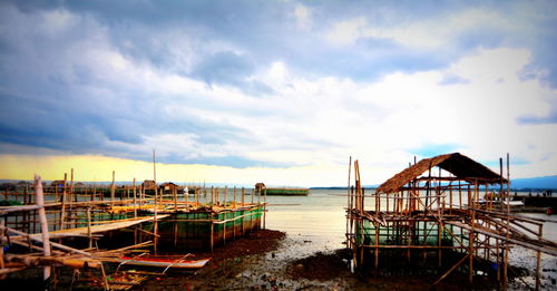 Pier on sea against cloudy sky