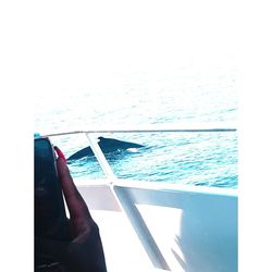 Person holding umbrella by sea against sky