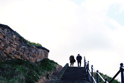 Rear view of people walking on steps against sky