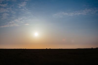 Scenic view of silhouette field against sky during sunset