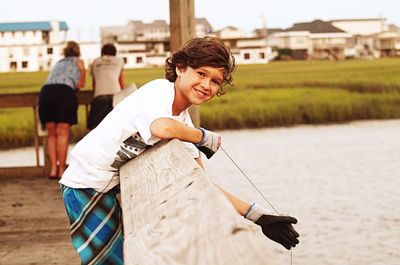 Portrait of boy crabbing on pier over lake