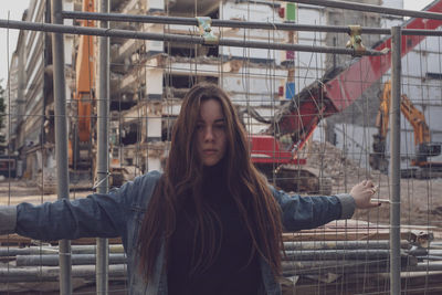 Young woman standing by fence