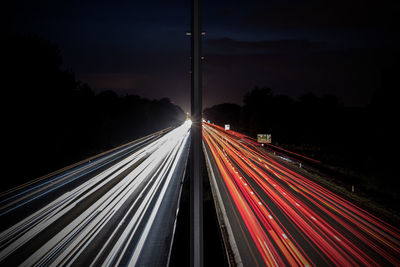 Light trails on road against sky at night