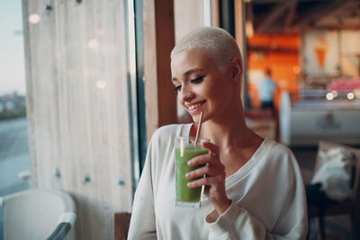 Smiling woman drinking smoothie at cafe