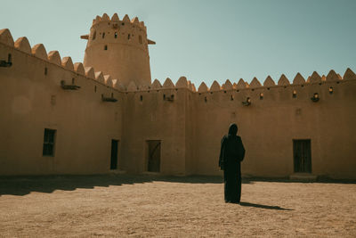 Rear view of man standing on fort against sky