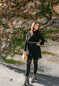 Full length portrait of attractive young woman with beautiful hair. black dress, standing.