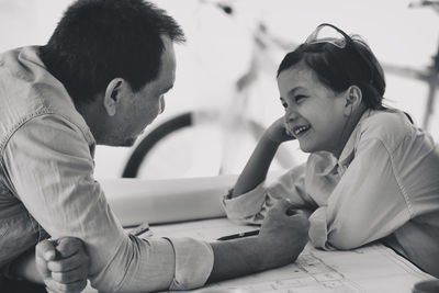 Portrait of man sitting on table with his daughter in the garage workshop.family bonding