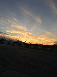 Airplane on runway against sky during sunset