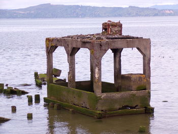 Old wooden structure in lake against sky