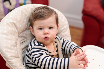 Cute young toddler messily eating in his high chair