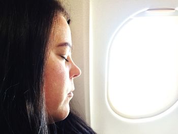 Close-up portrait of woman looking through airplane window