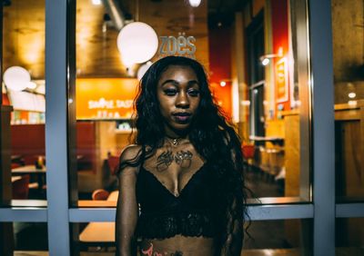 Portrait of woman standing against illuminated building