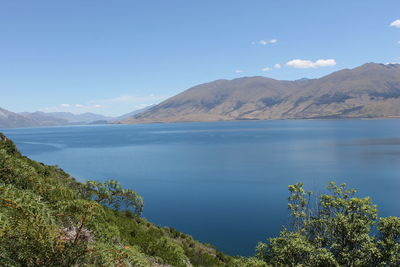 Scenic view of lake and mountains against blue sky