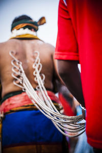 Rear view of boy holding chains pierced into man during thaipusam festival