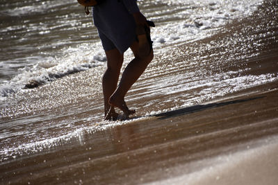 Low section of man walking on beach