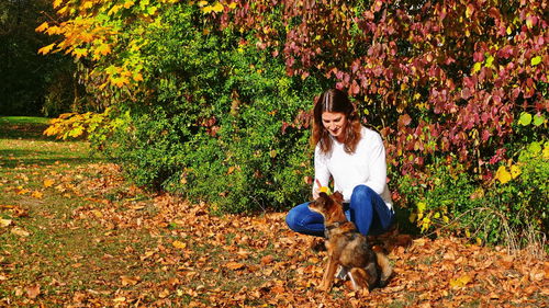Woman with dog on leaves during autumn