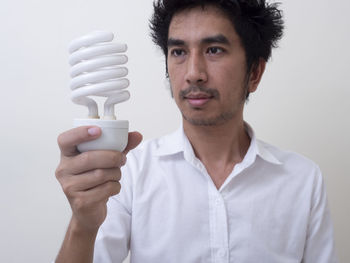 Portrait of young man holding white against wall