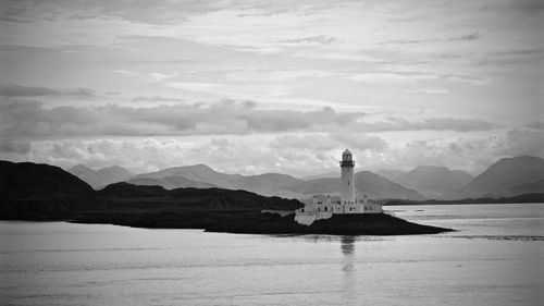 Lighthouse by sea against sky