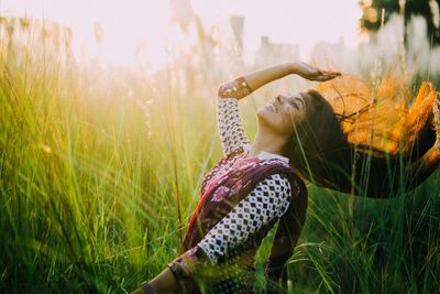 Woman tossing hair on field during sunset