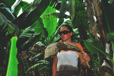 Young woman standing by banana trees