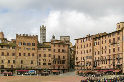 Buildings in city against cloudy sky