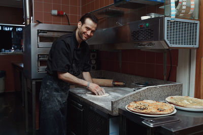 Midsection of male chef preparing italian pizza in kitchen