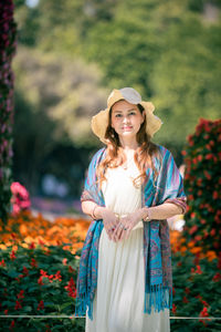 Portrait of smiling young woman standing against plants