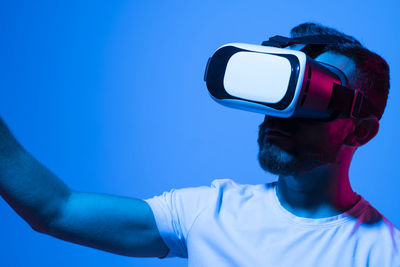 Side view of man holding mask against blue background