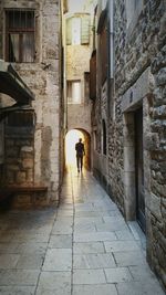 Rear view of man walking on narrow street