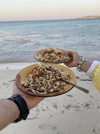 Midsection of person holding ice cream on beach