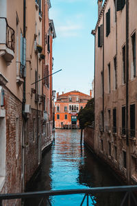 Canal amidst buildings in city against sky