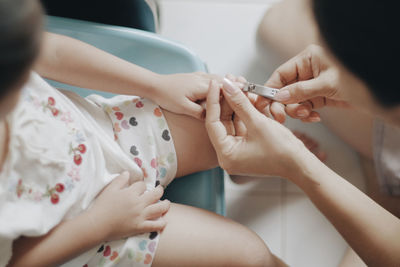 Midsection of girl having nails cut