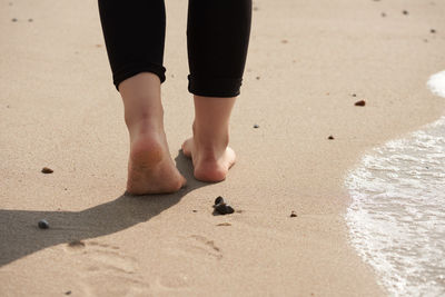 Low section of woman walking on sand