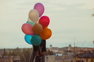 Multi colored balloons in city against sky